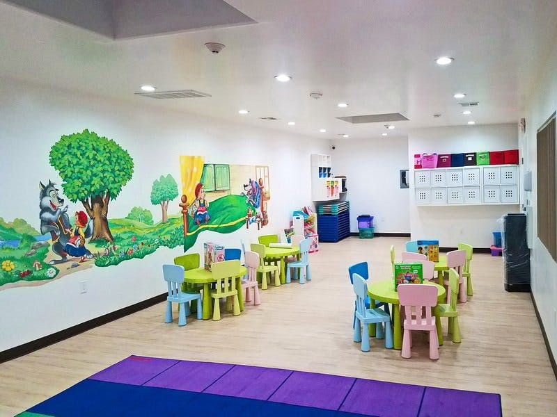 Classroom with colorful tables and chairs, mural on wall