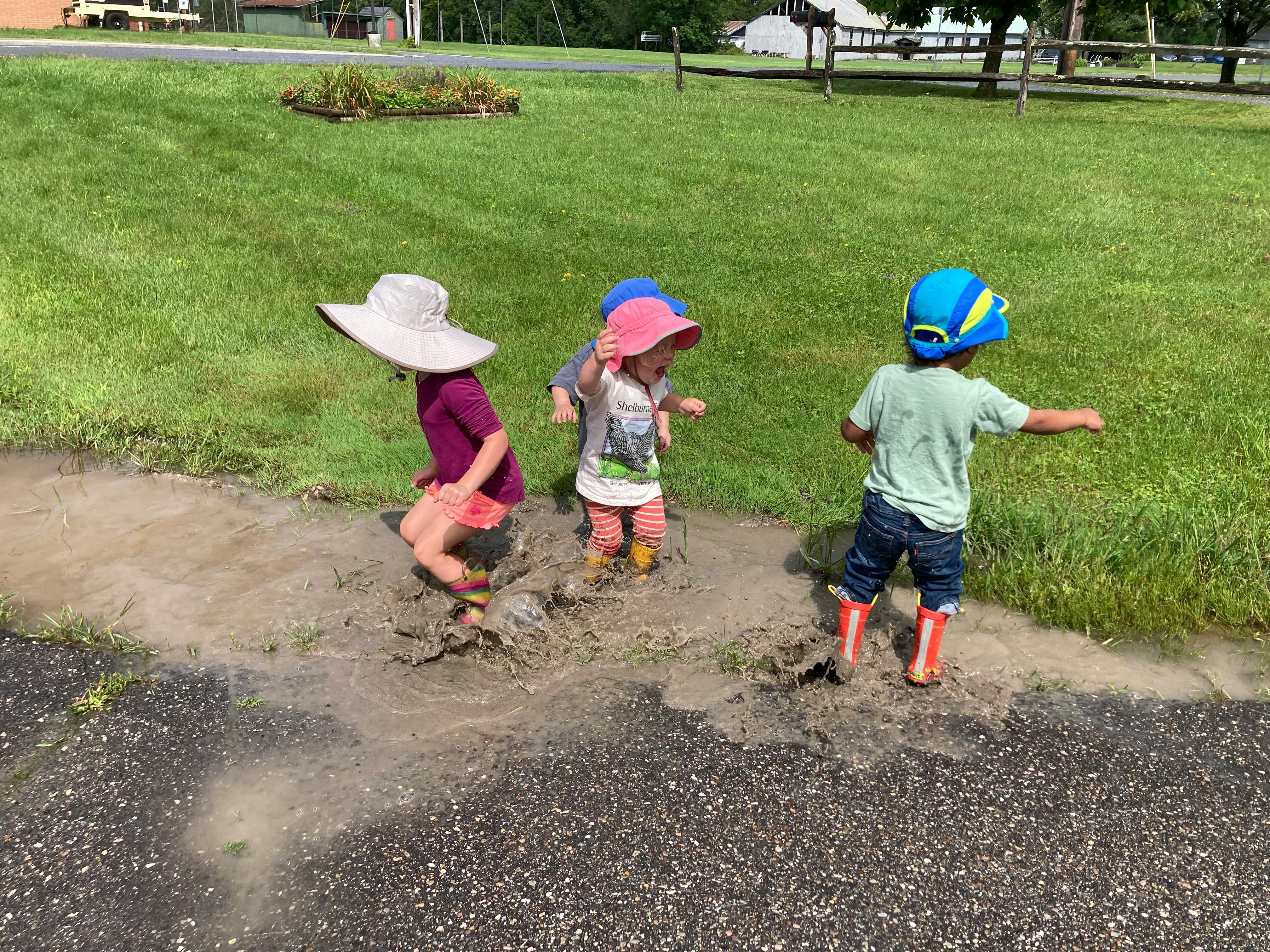 Three children playing in a muddy puddle
