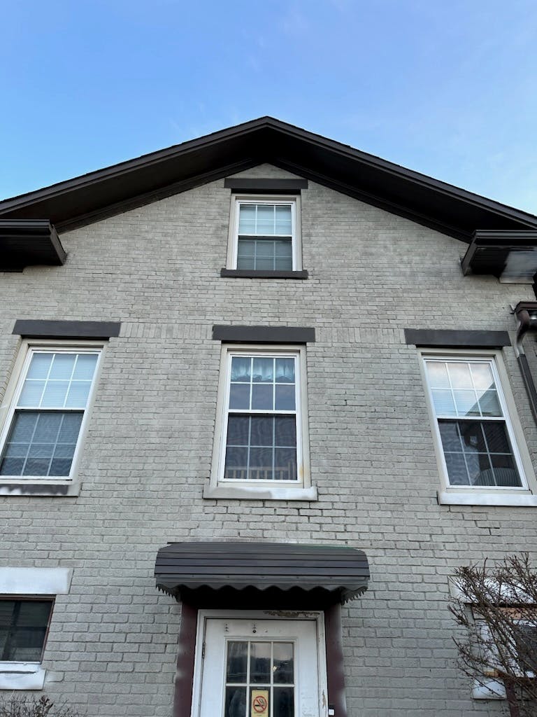 Front of a brick building with multiple windows and a door with an awning