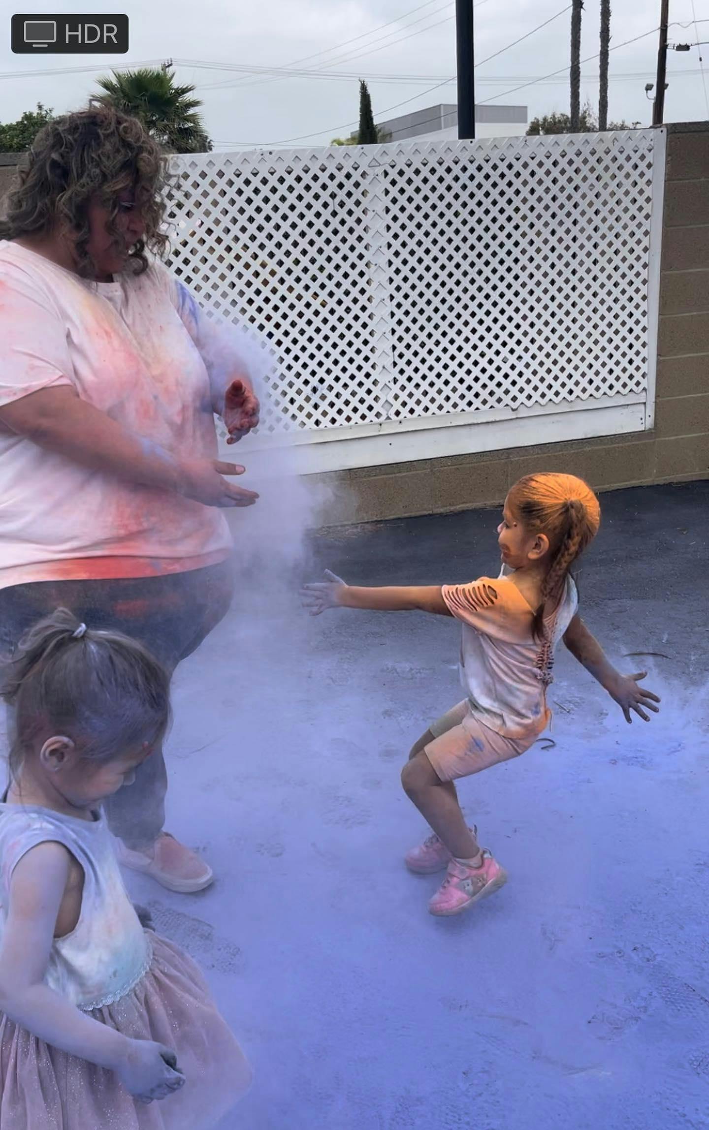 Person and two children playing with colorful powder