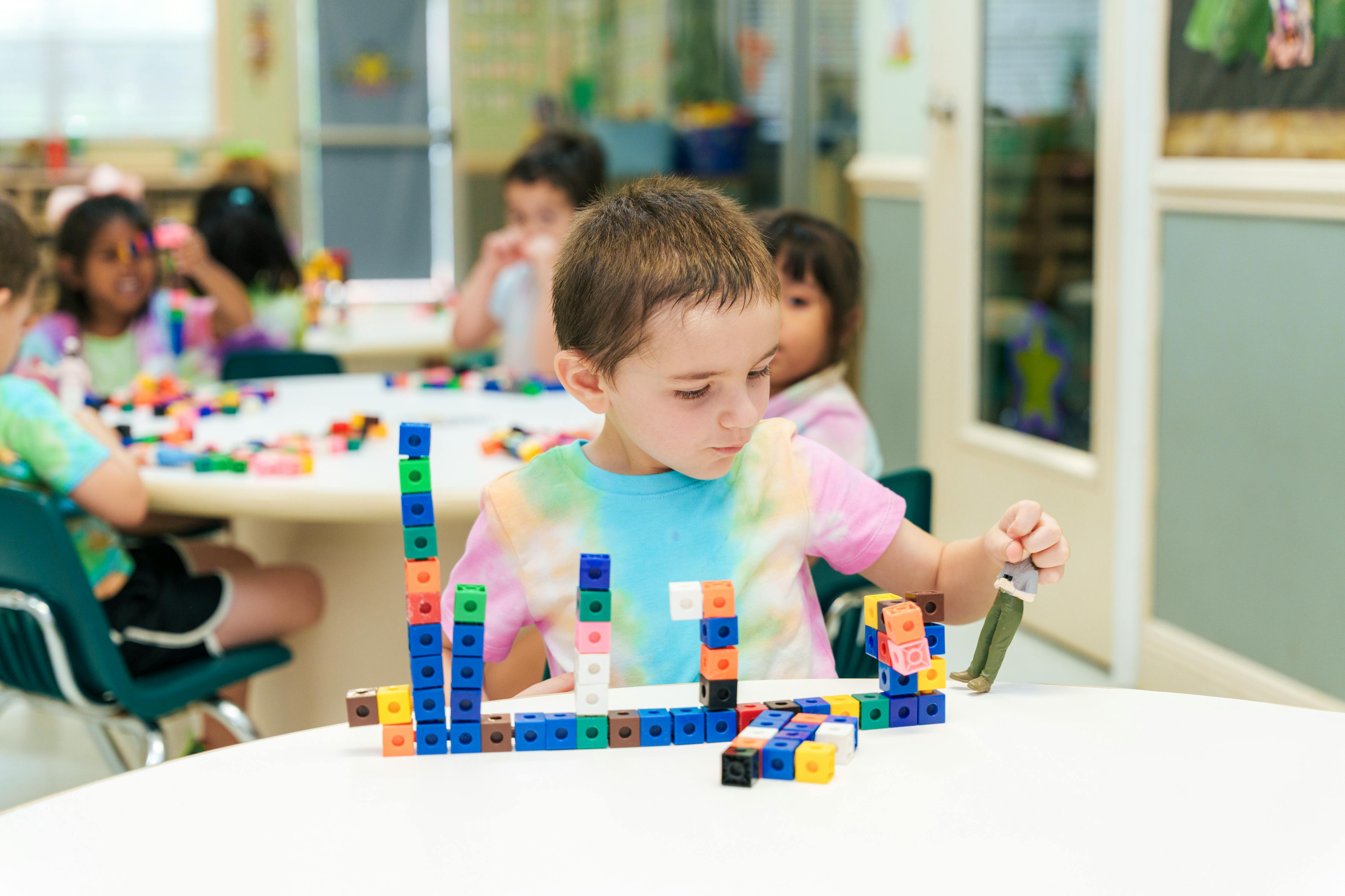Child building with colorful interlocking blocks in a classroom