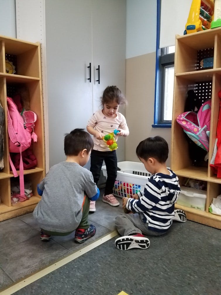 Three children playing with toys in a classroom