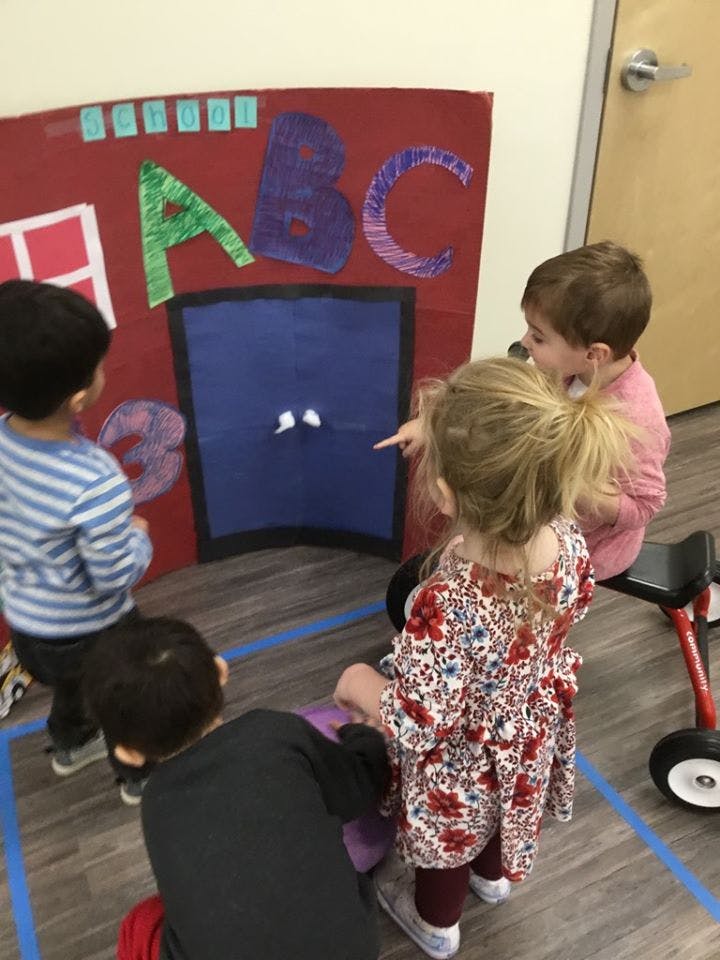 Children gathered around a large ABC sign with a blue door