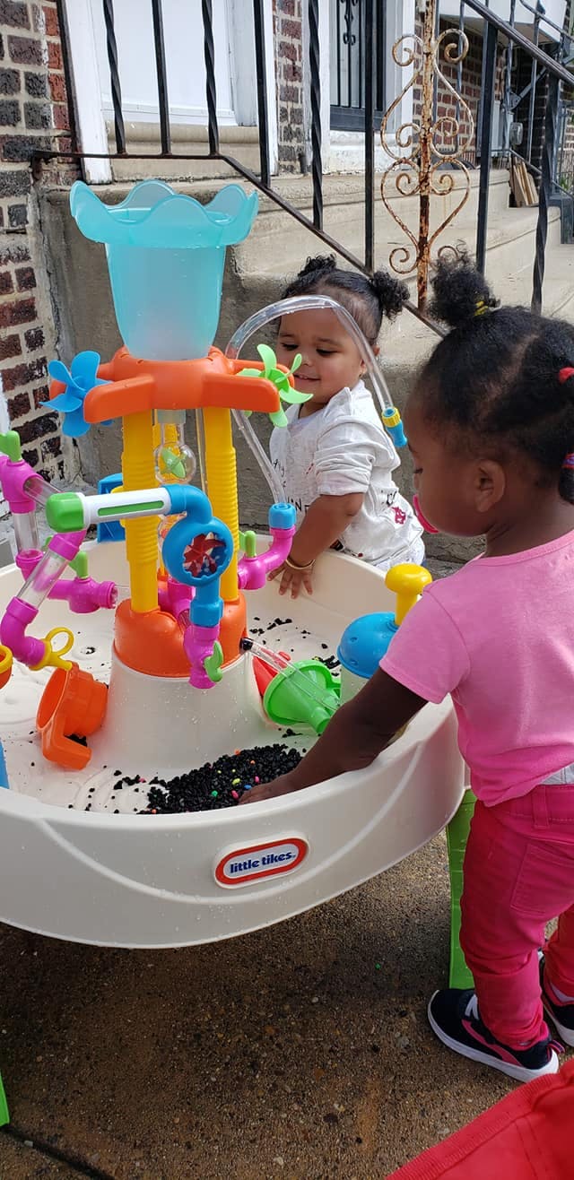 Two children playing with a water table outdoors