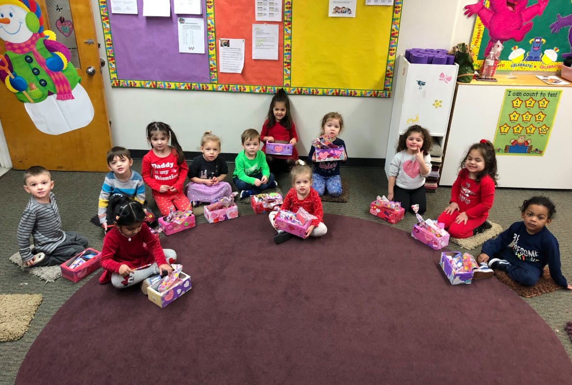 Children sitting on a rug with small boxes in a classroom