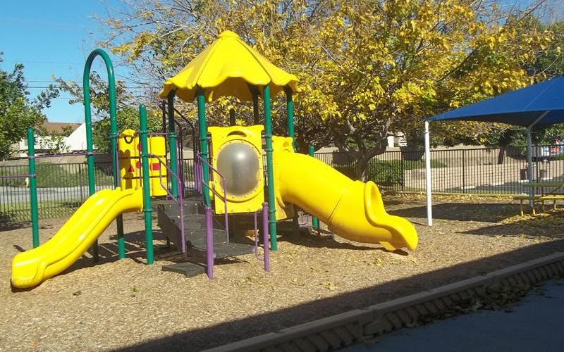 Yellow and green playground structure with slides