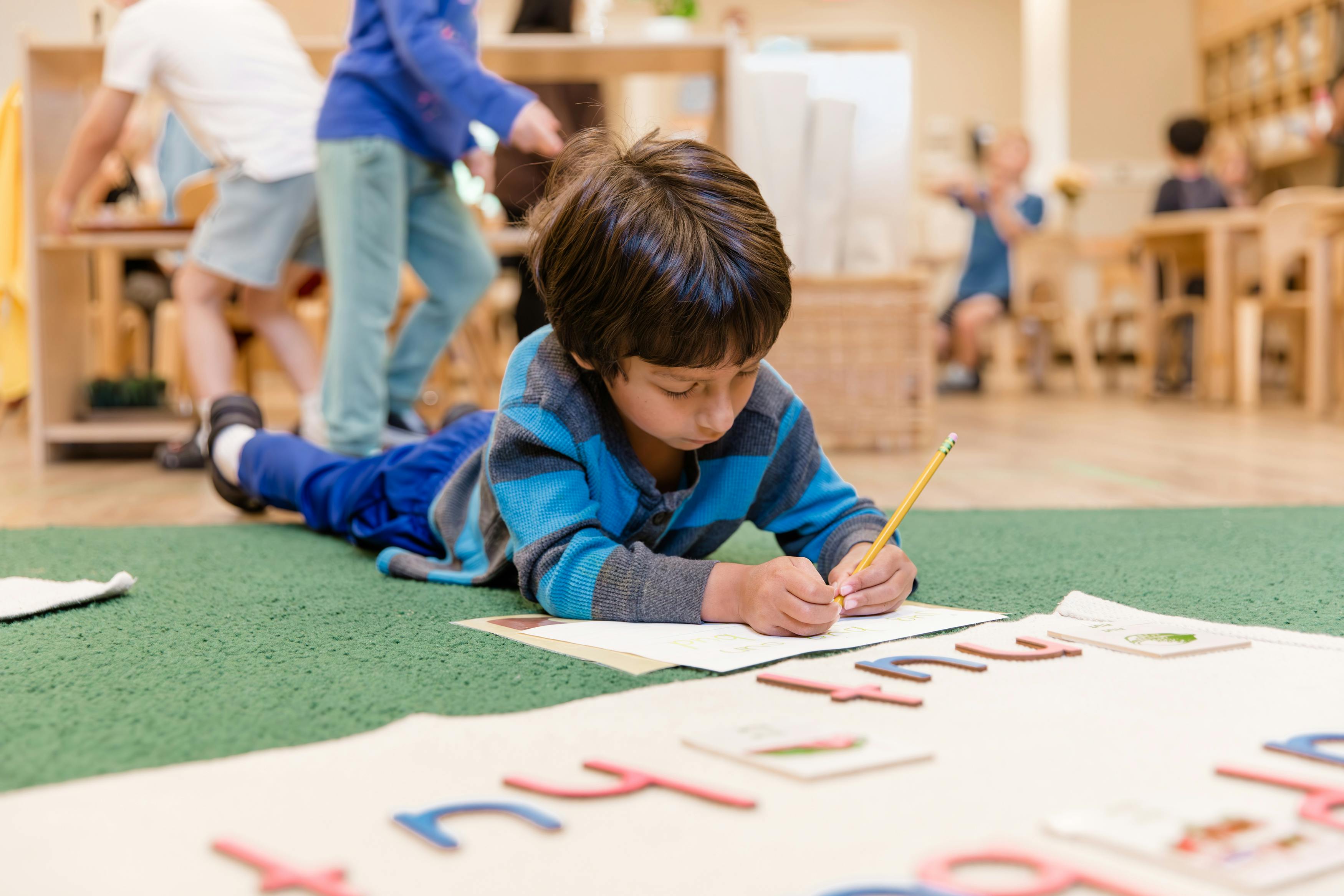Child lying on floor writing with a pencil