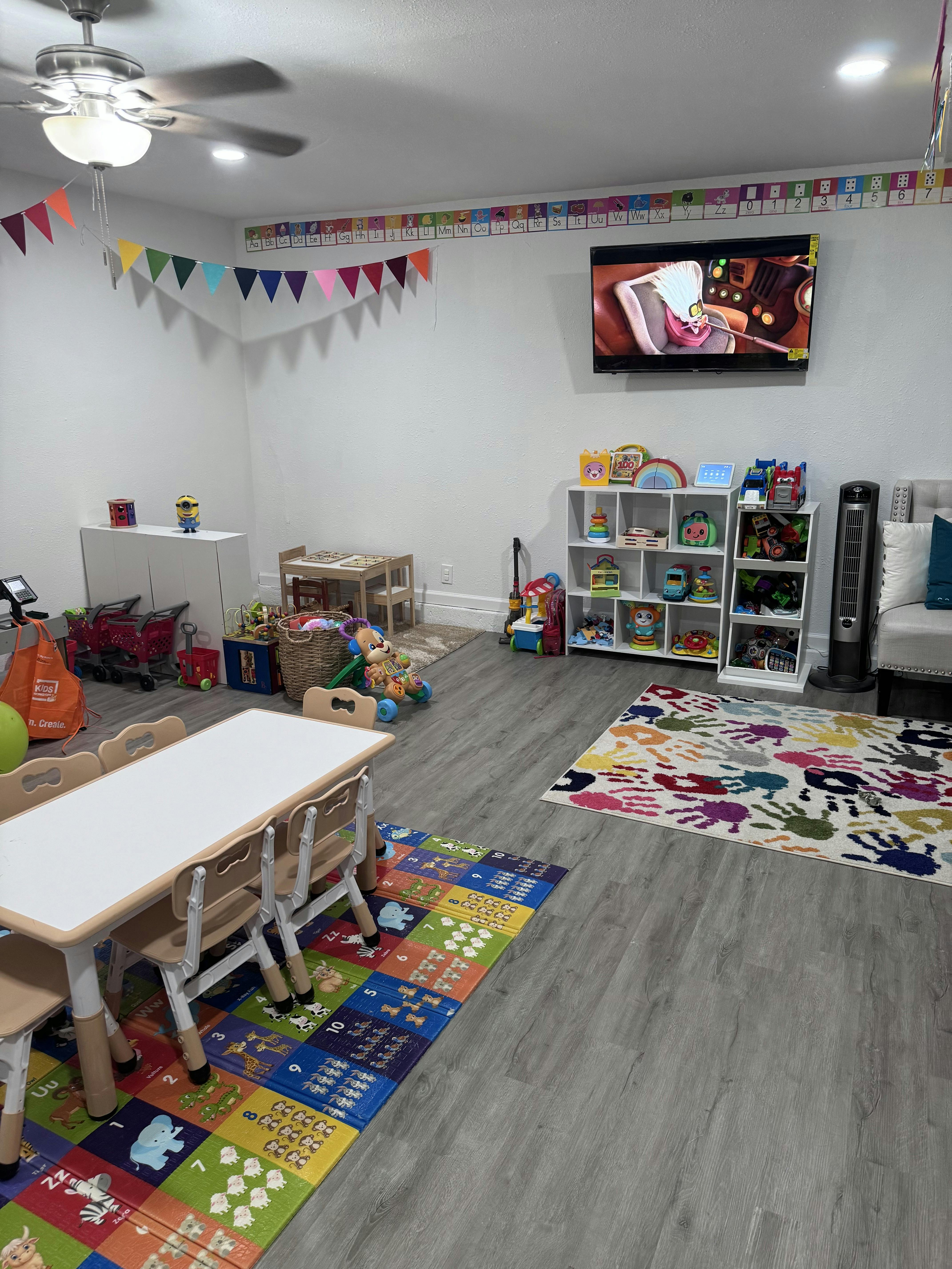 Playroom with small tables and chairs, toys, and a television on-wall television