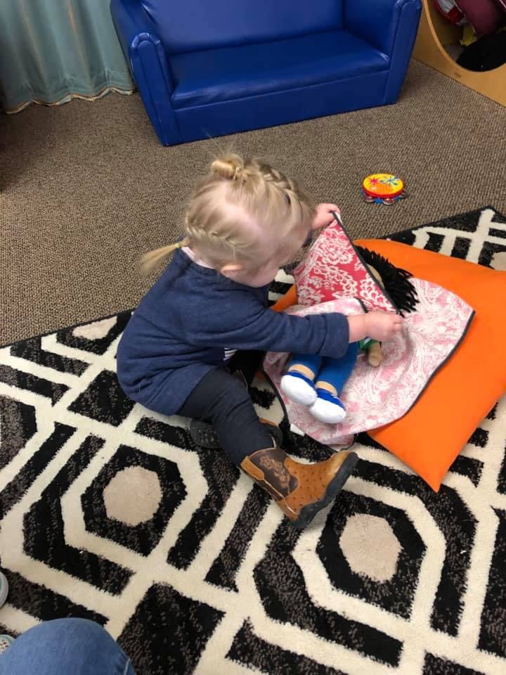 Child playing with a doll on a patterned rug