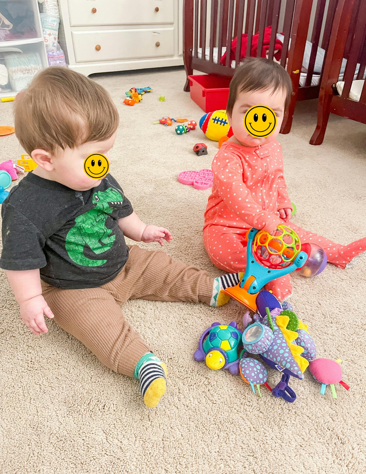 Two children sitting on a carpeted floor with toys
