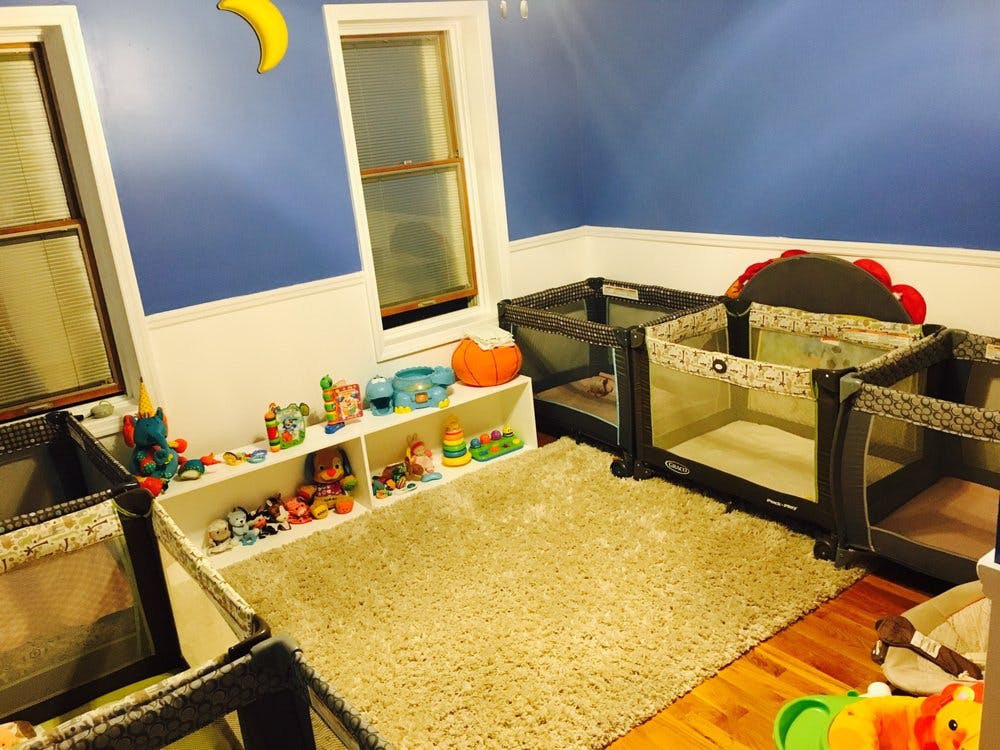 Room with multiple playpens, a rug, and a shelf with toys