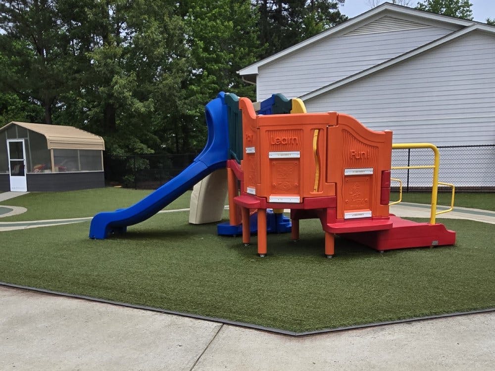 Colorful playground equipment with blue slide on green artificial turf