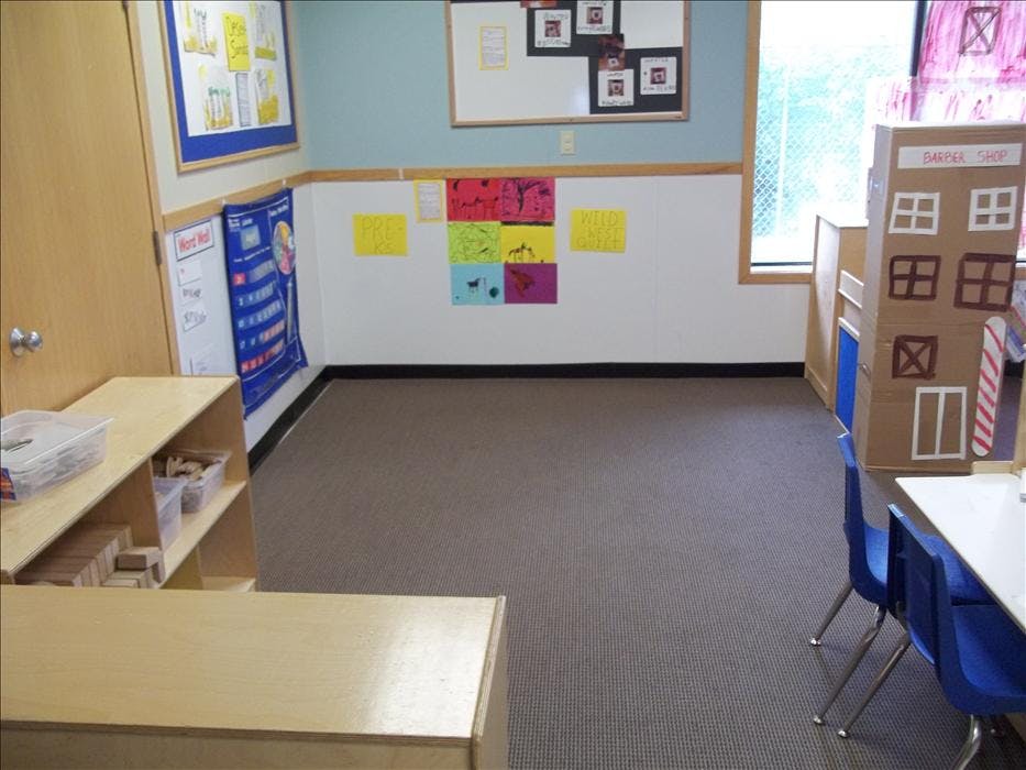 Empty classroom with brown carpet and children's artwork on the walls