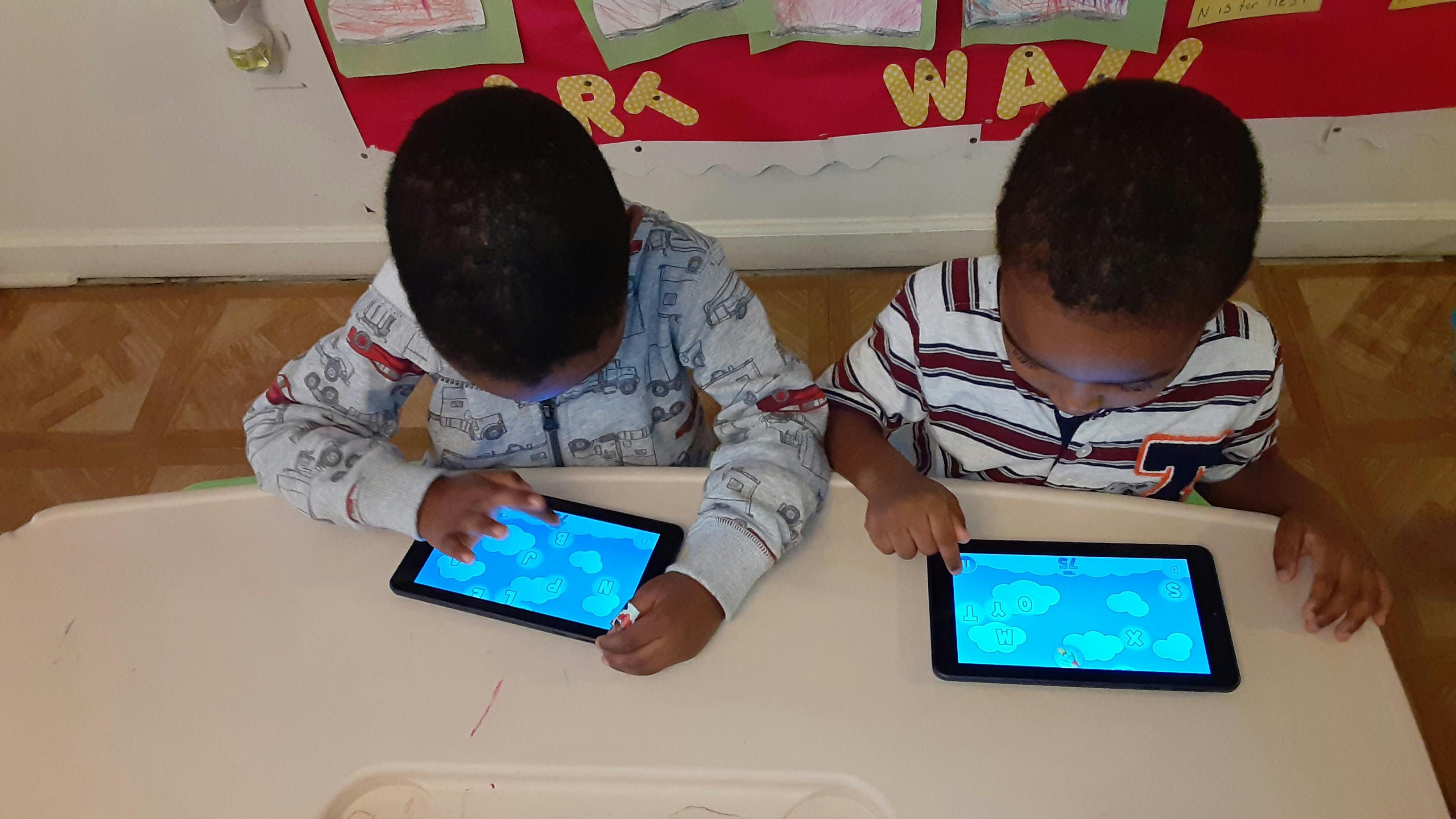 Two children looking at and touching tablets