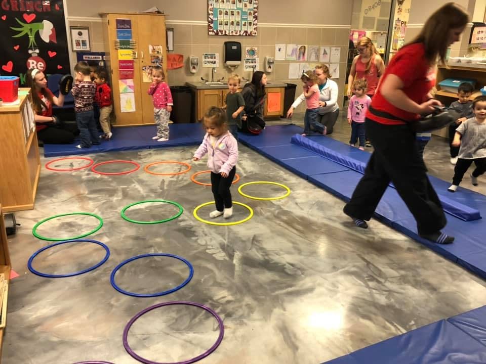 Children and adults in a classroom with hula hoops on the floor