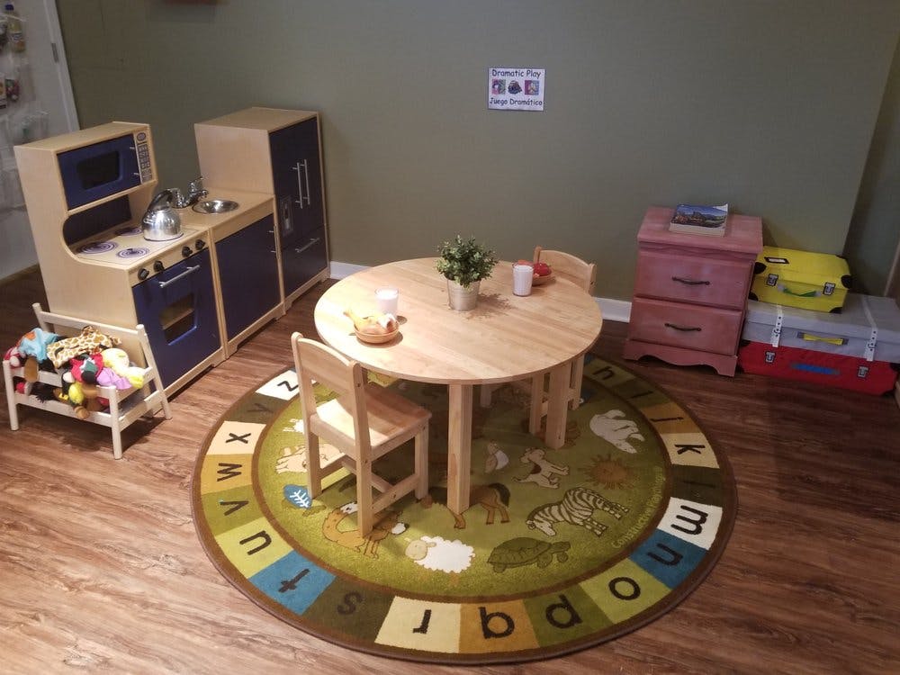 Playroom with a toy kitchen, small table and chairs, and an alphabet rug