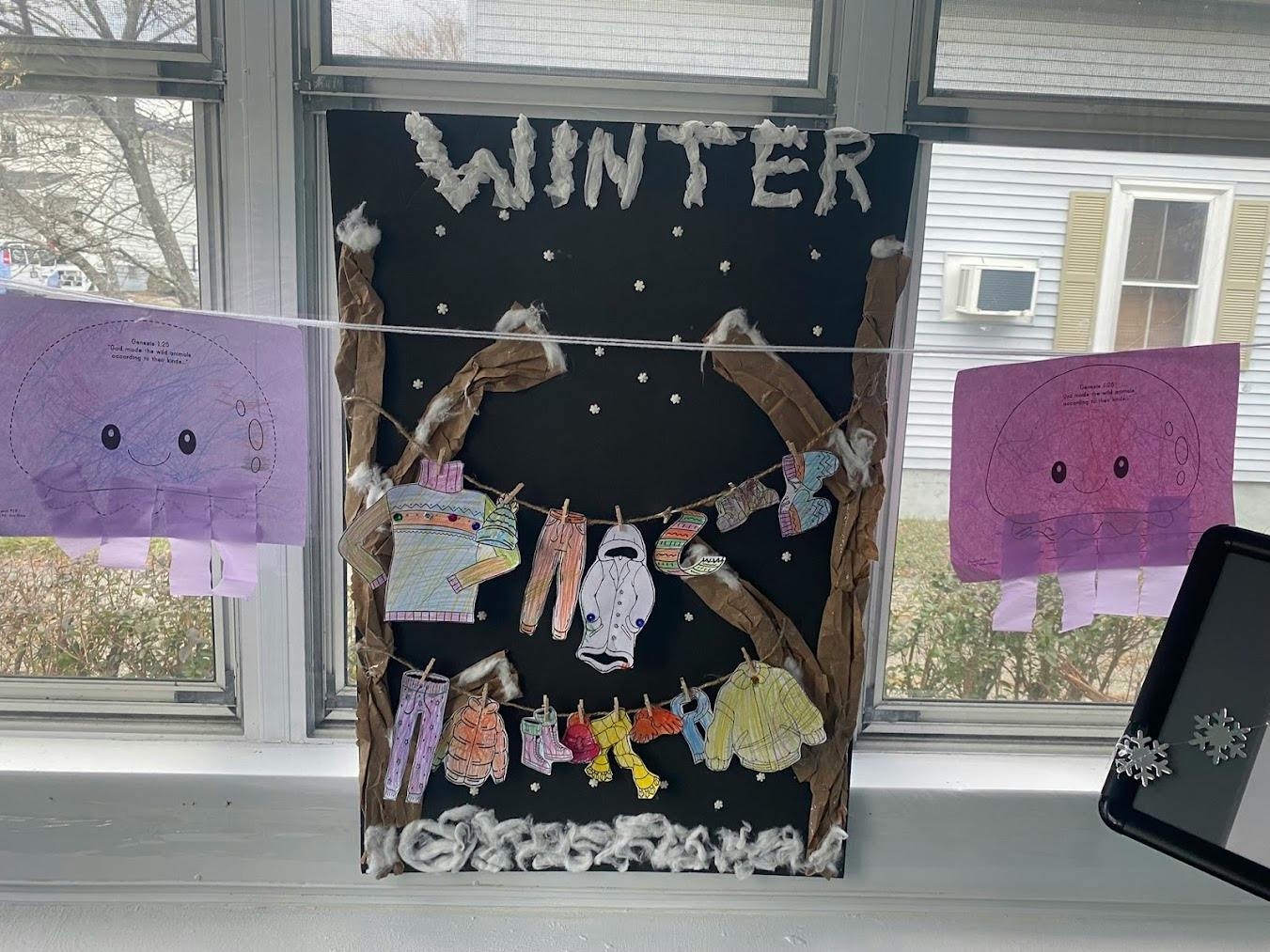 Winter-themed classroom display with paper winter clothing hanging on a line