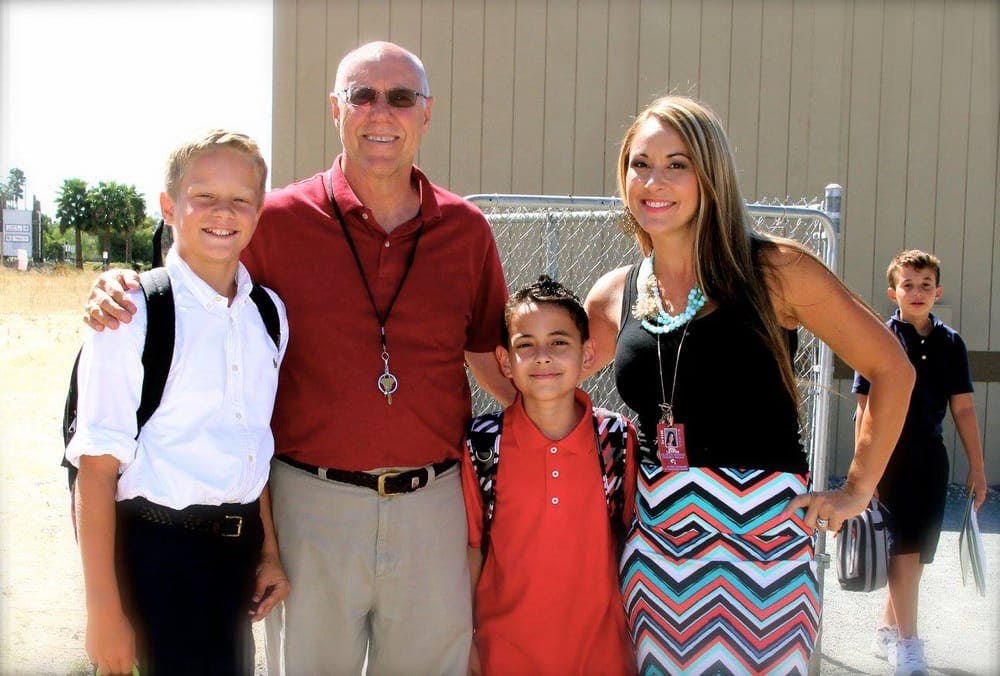 Two adults and two children standing together, one child with a backpack