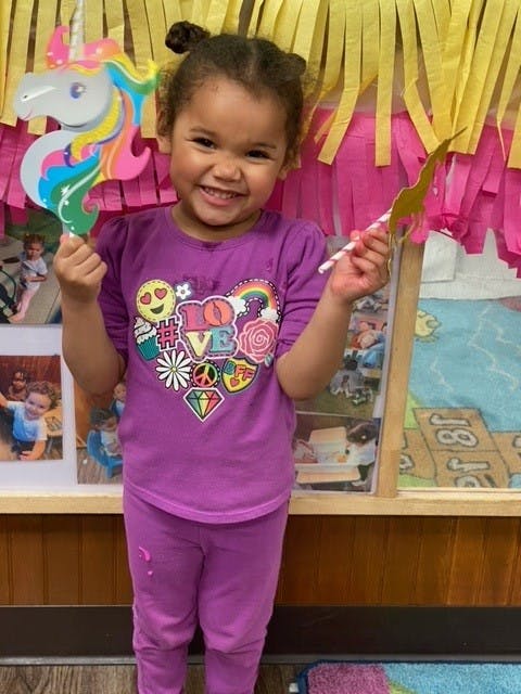 Child holding a colorful unicorn cutout and a gold star wand