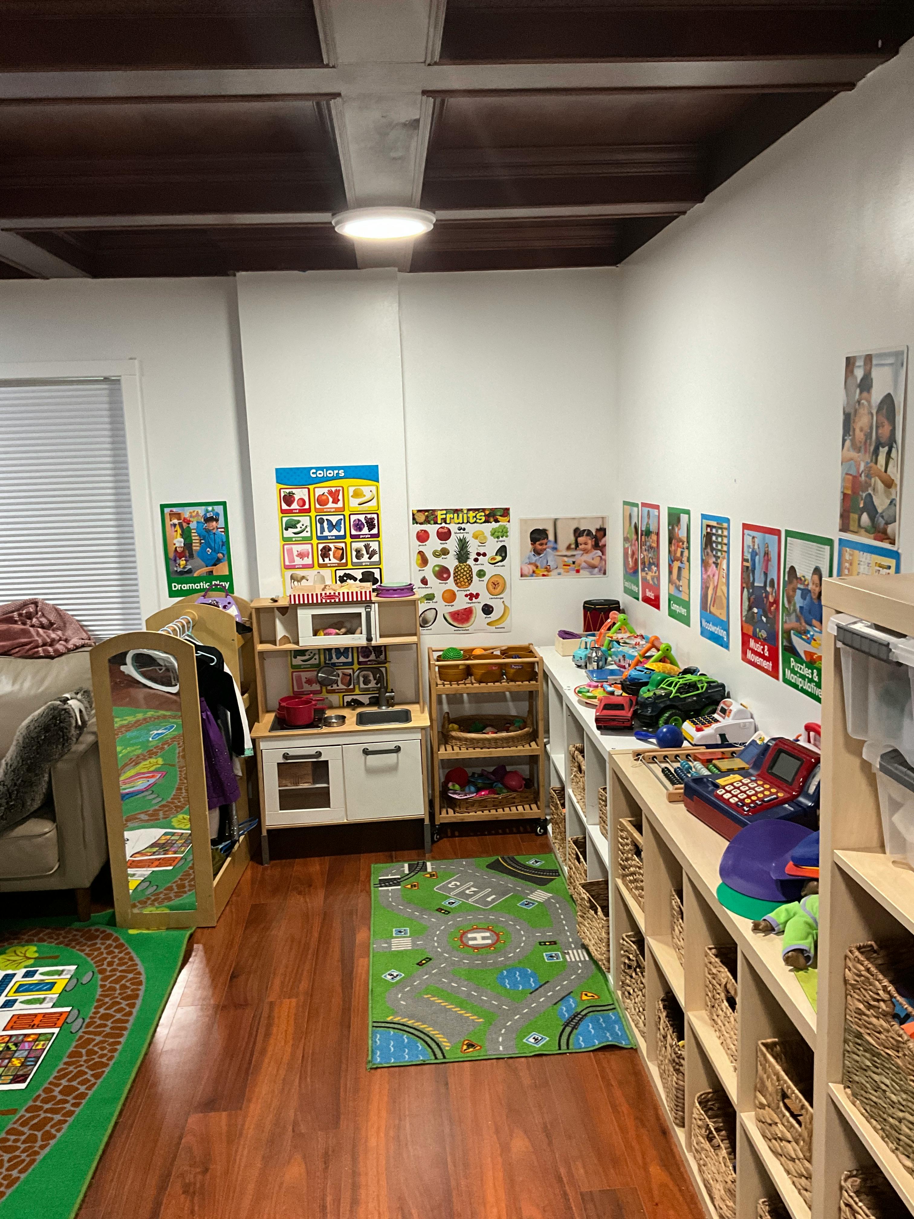 Playroom with toy kitchen, shelves of toys, and play mats on the floor