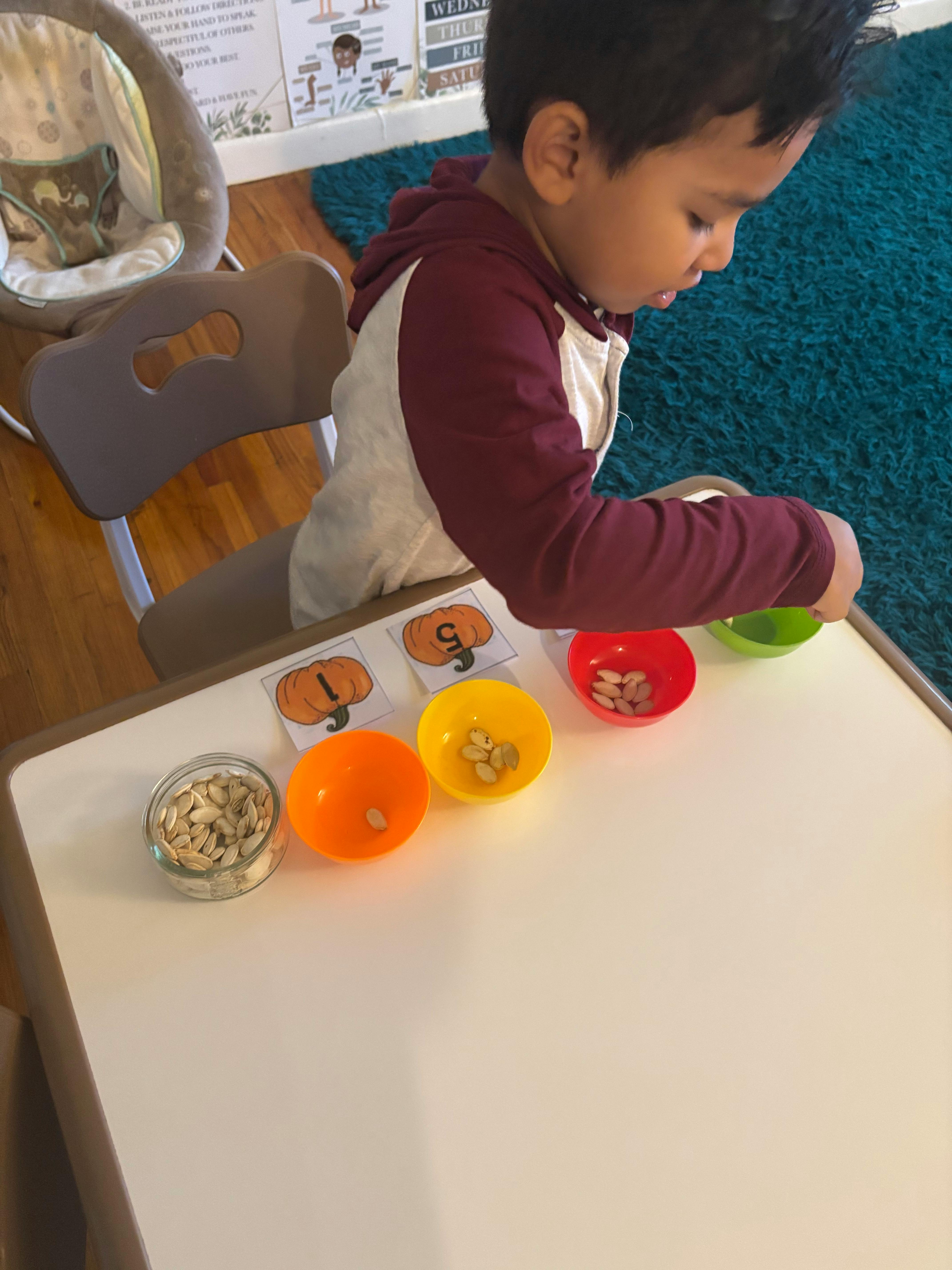 Child sorting seeds into small colorful bowls on a table