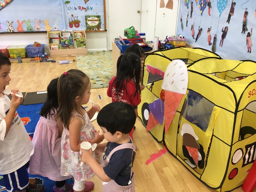 Children playing in a classroom with a yellow school bus play tent