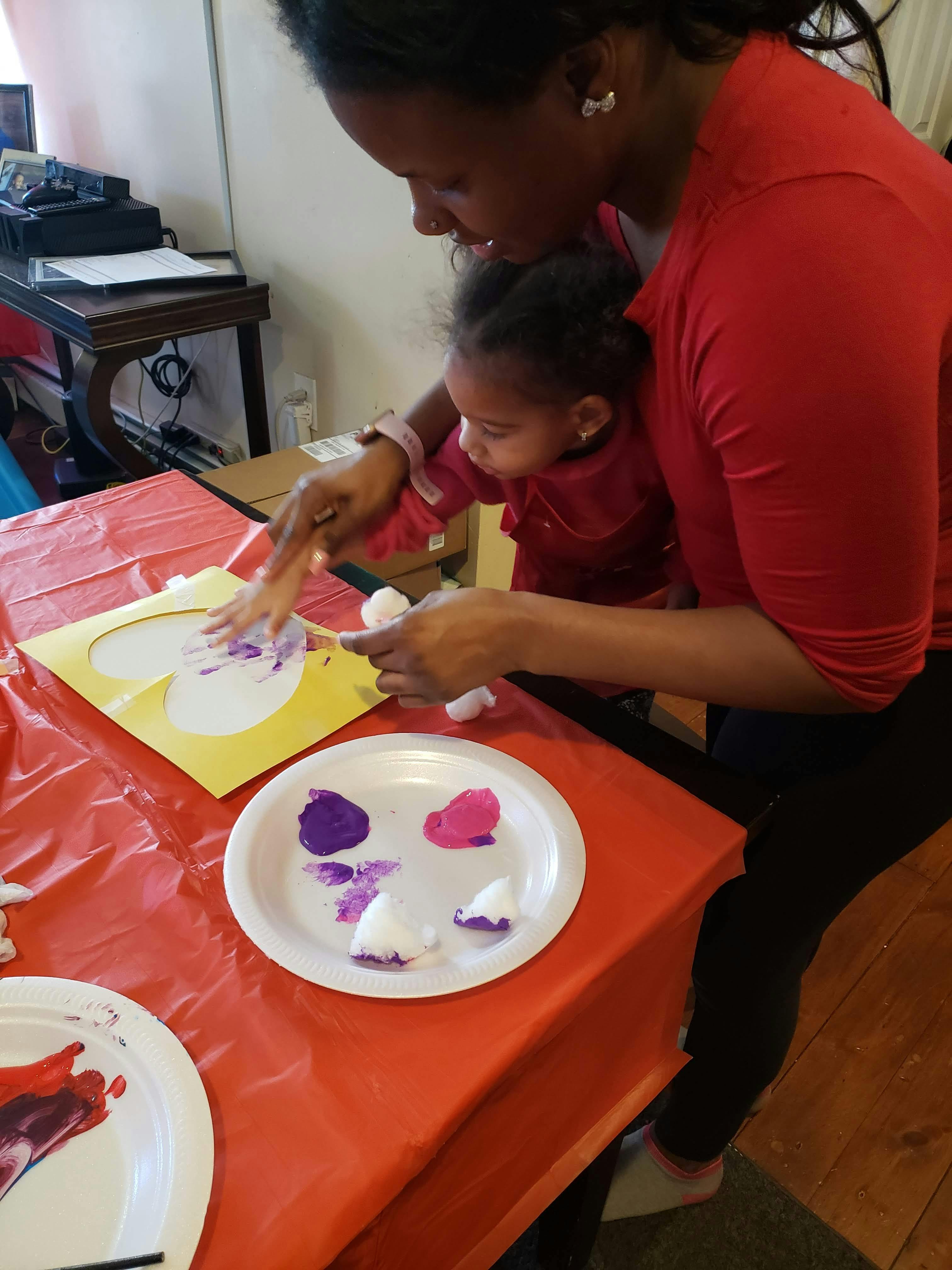 Person and child painting a heart shape on paper