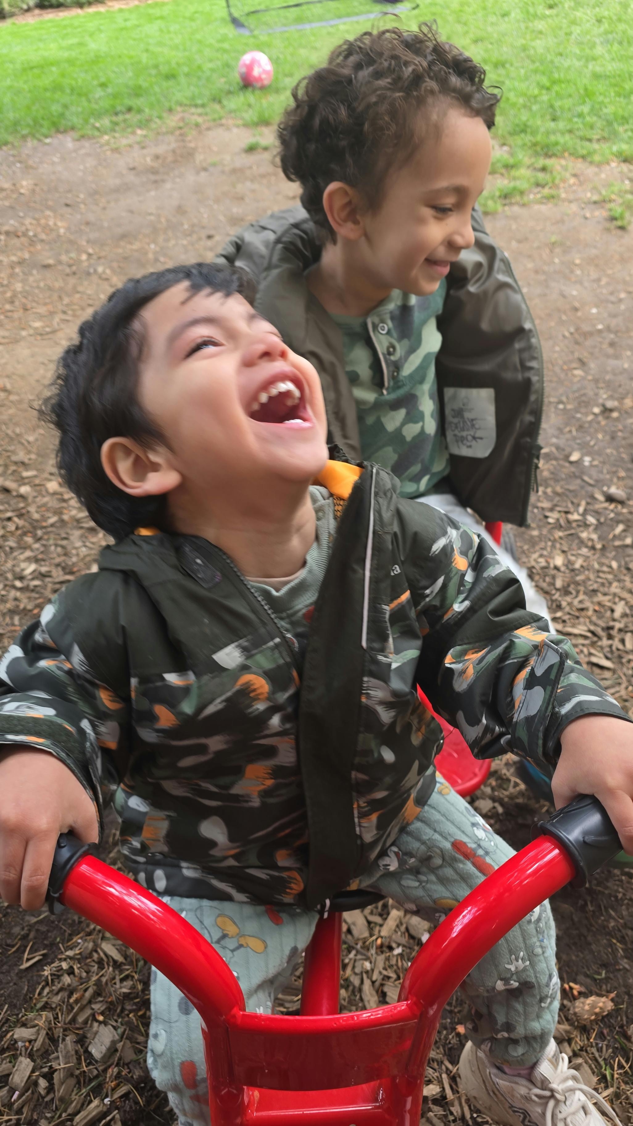 Two children on a red tricycle