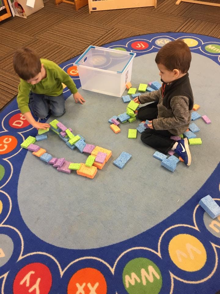 Two children playing with colorful building blocks on a rug