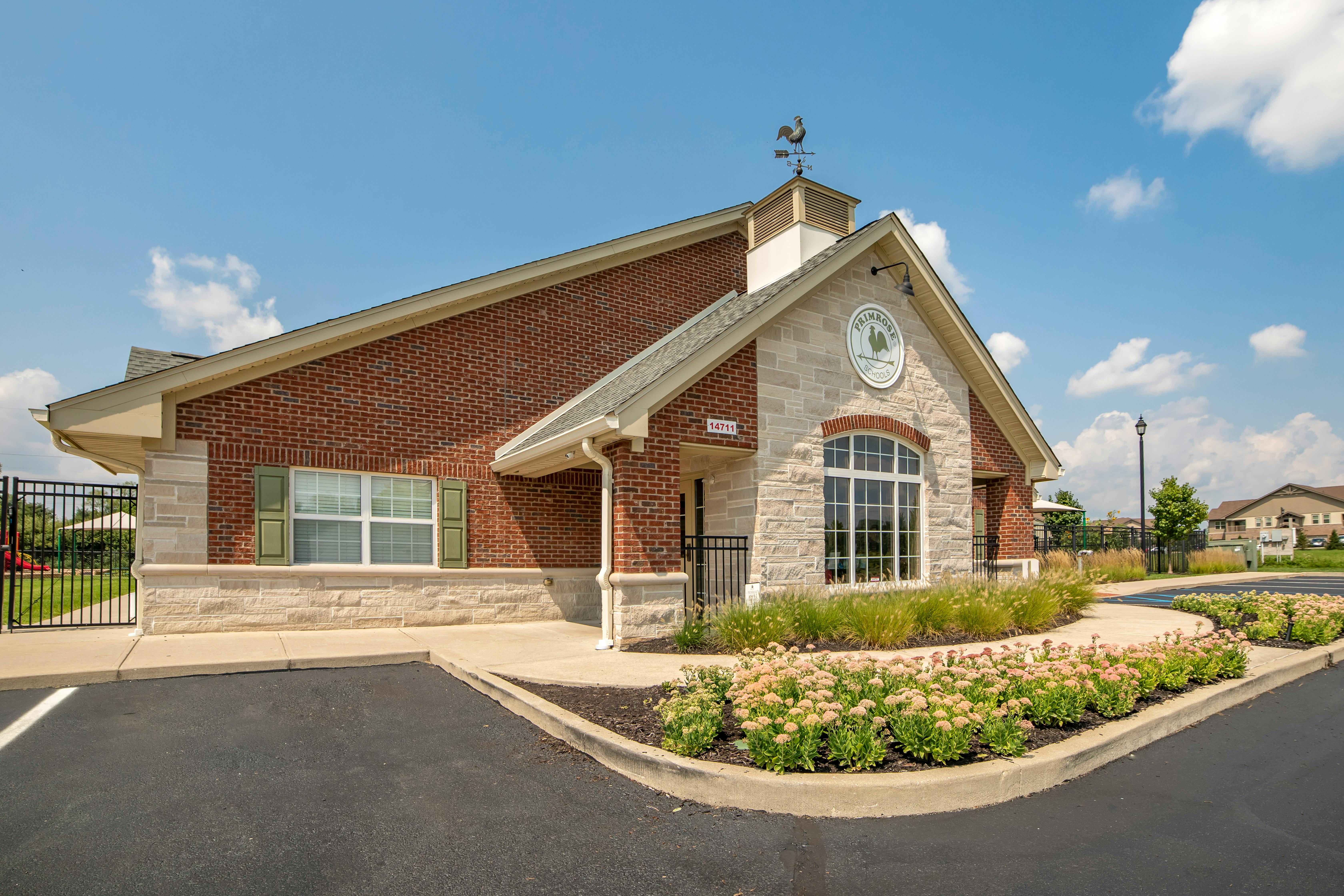 Brick and stone building with a "Primrose Schools" sign and a rooster weathervane