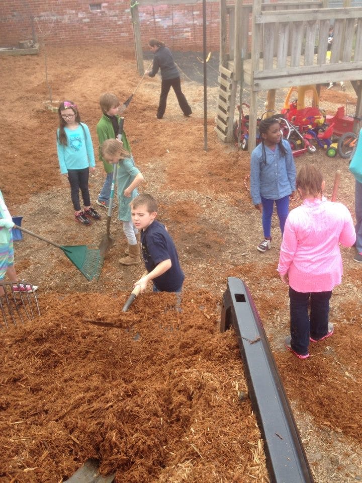 Children and adults spreading mulch on a playground