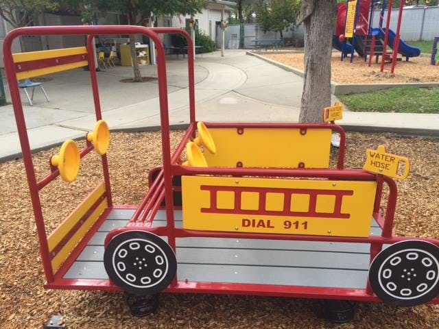Red and yellow fire truck play structure with "DIAL 911" on the side