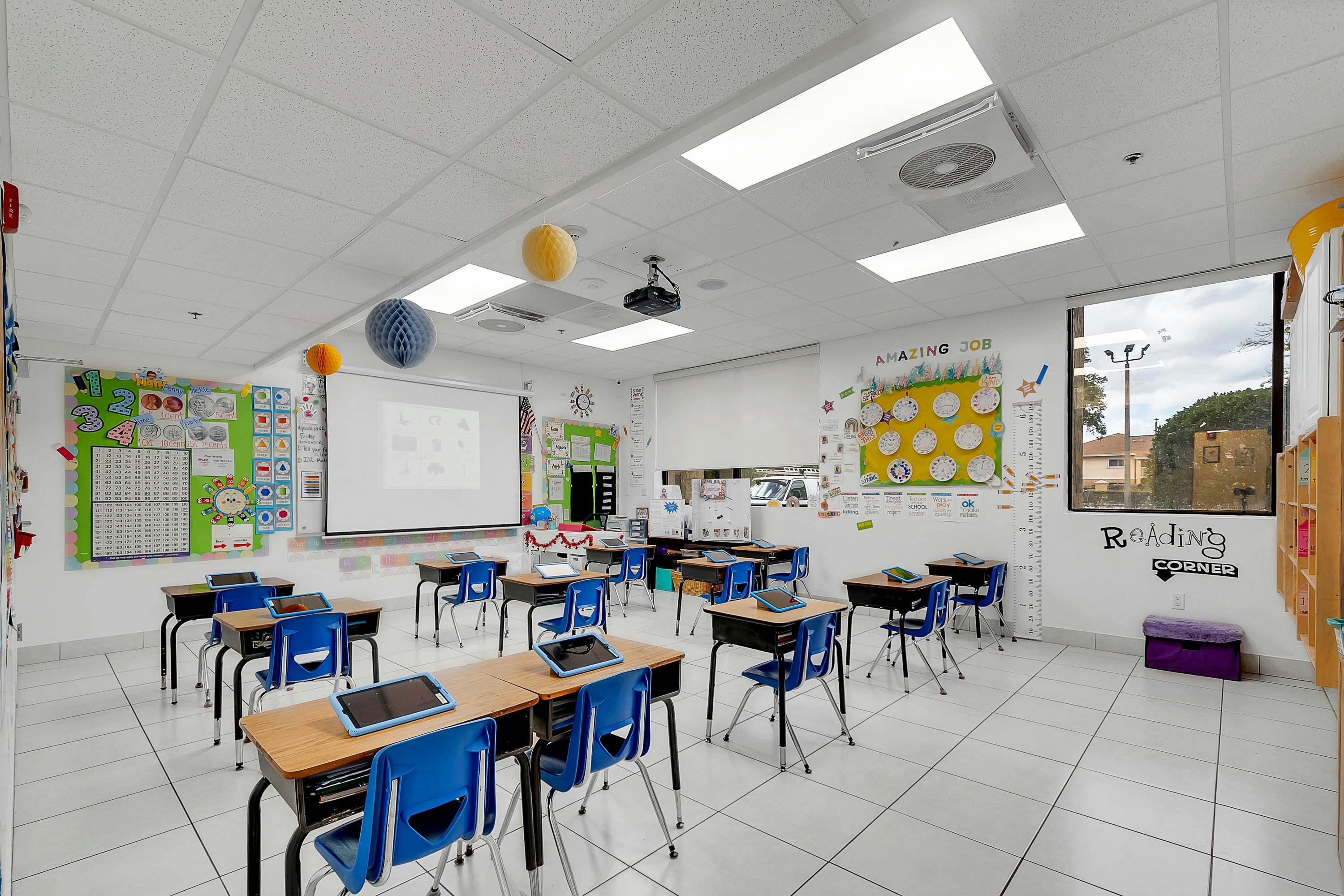 Empty classroom with desks, chairs, and a projector screen