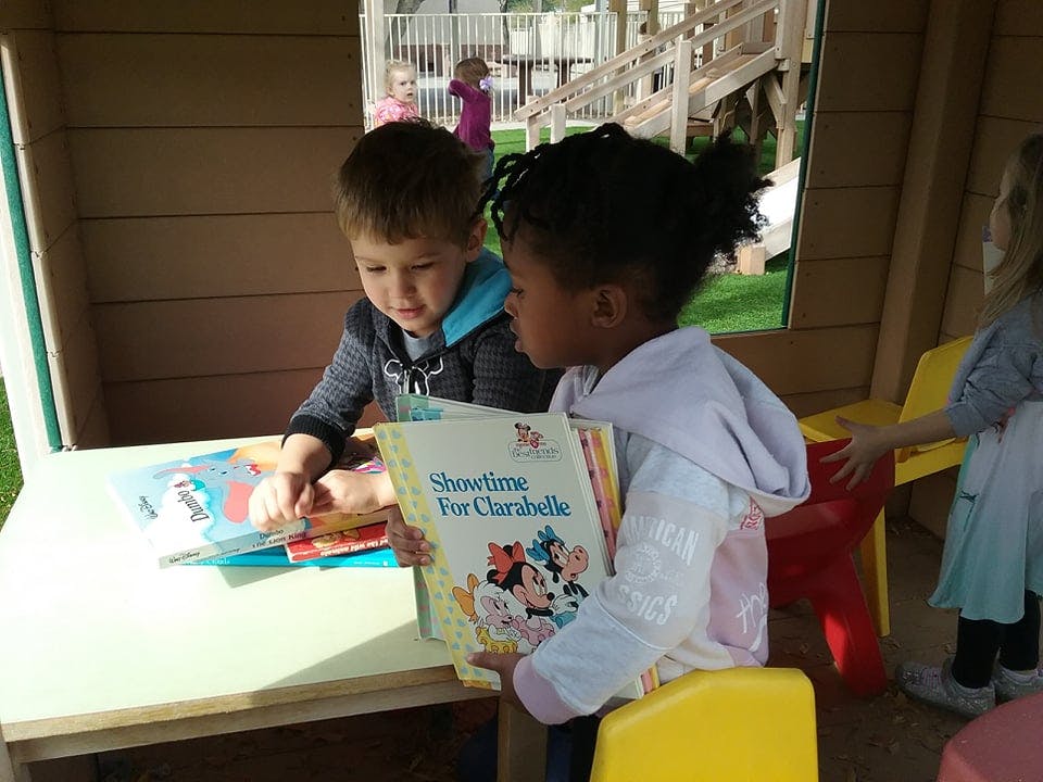 Two children reading books at a table