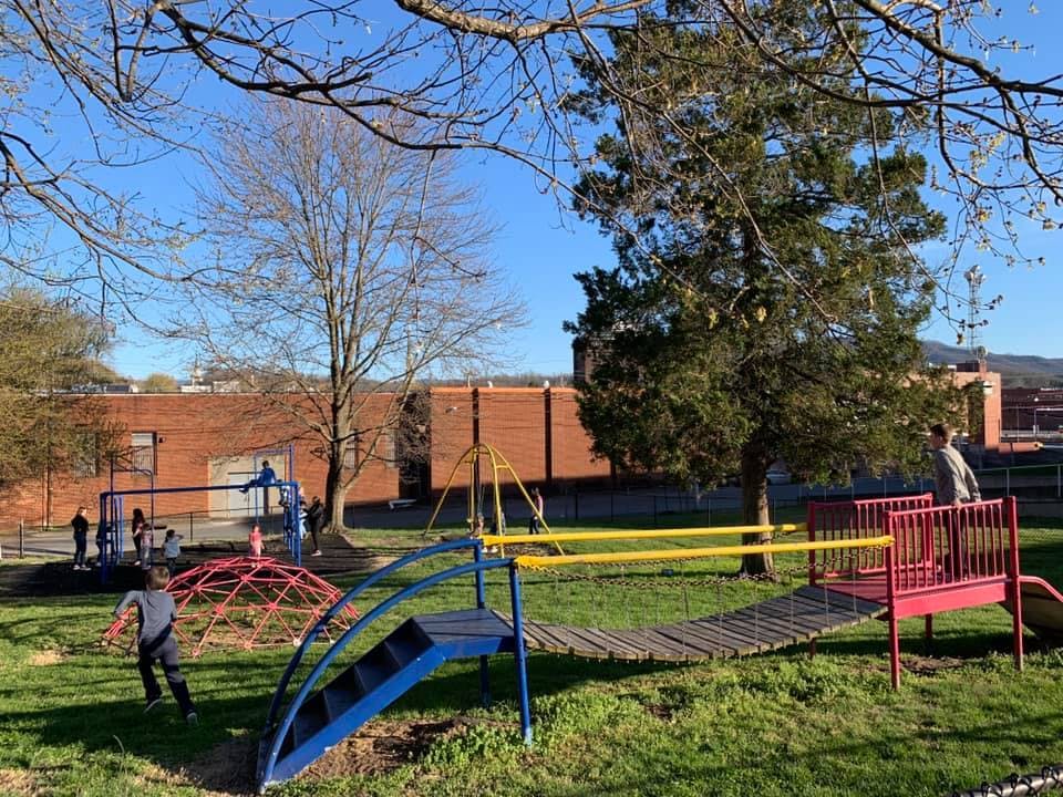 Children playing on playground equipment with a brick building in the background