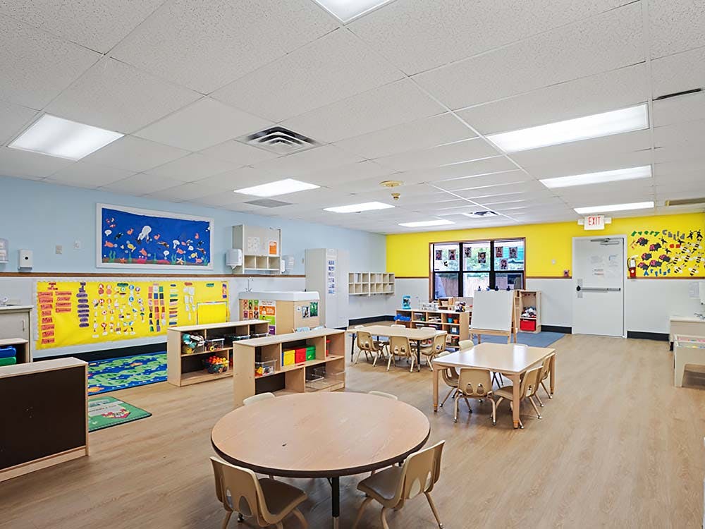 Empty children's classroom with small tables and chairs