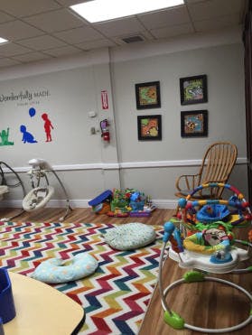 Infant and toddler play area with colorful rug and toys