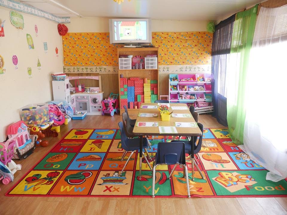 Playroom with a colorful alphabet rug, small table and chairs, and toys