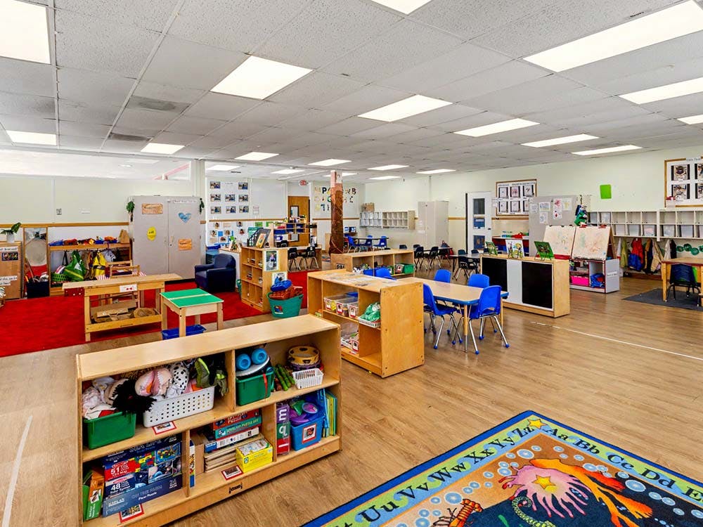 Empty classroom with small tables, chairs, and shelves