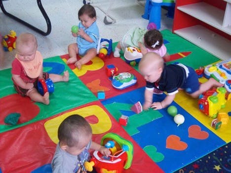 Multiple babies playing with toys on a colorful mat