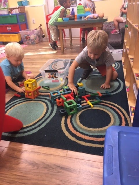 Two children playing with colorful building blocks on a rug
