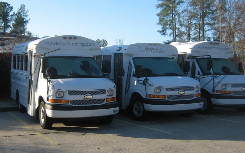 Three white buses with "knowledgelearning.com" on the top
