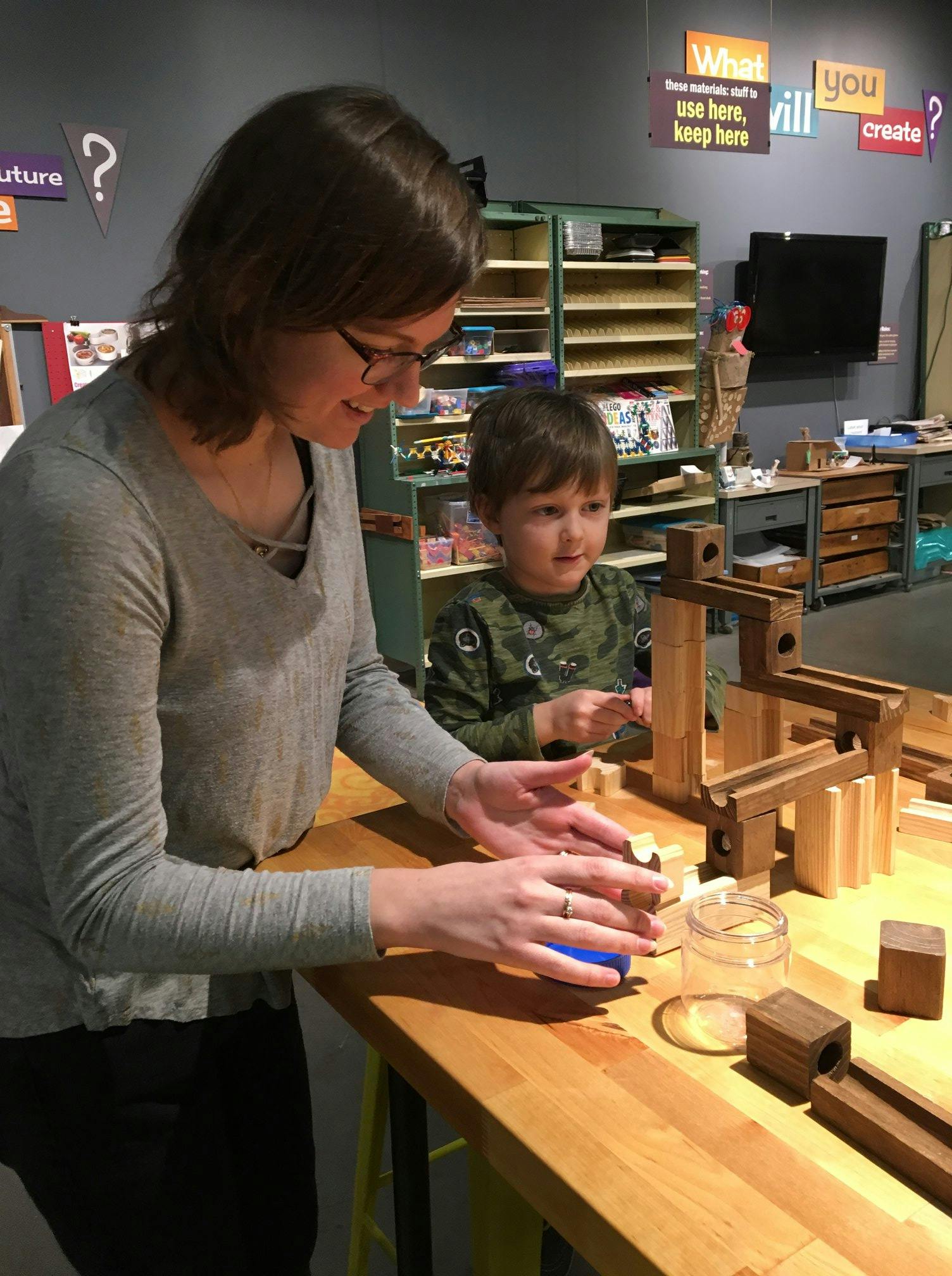 Adult and child playing with wooden blocks and plastic blocks on a table