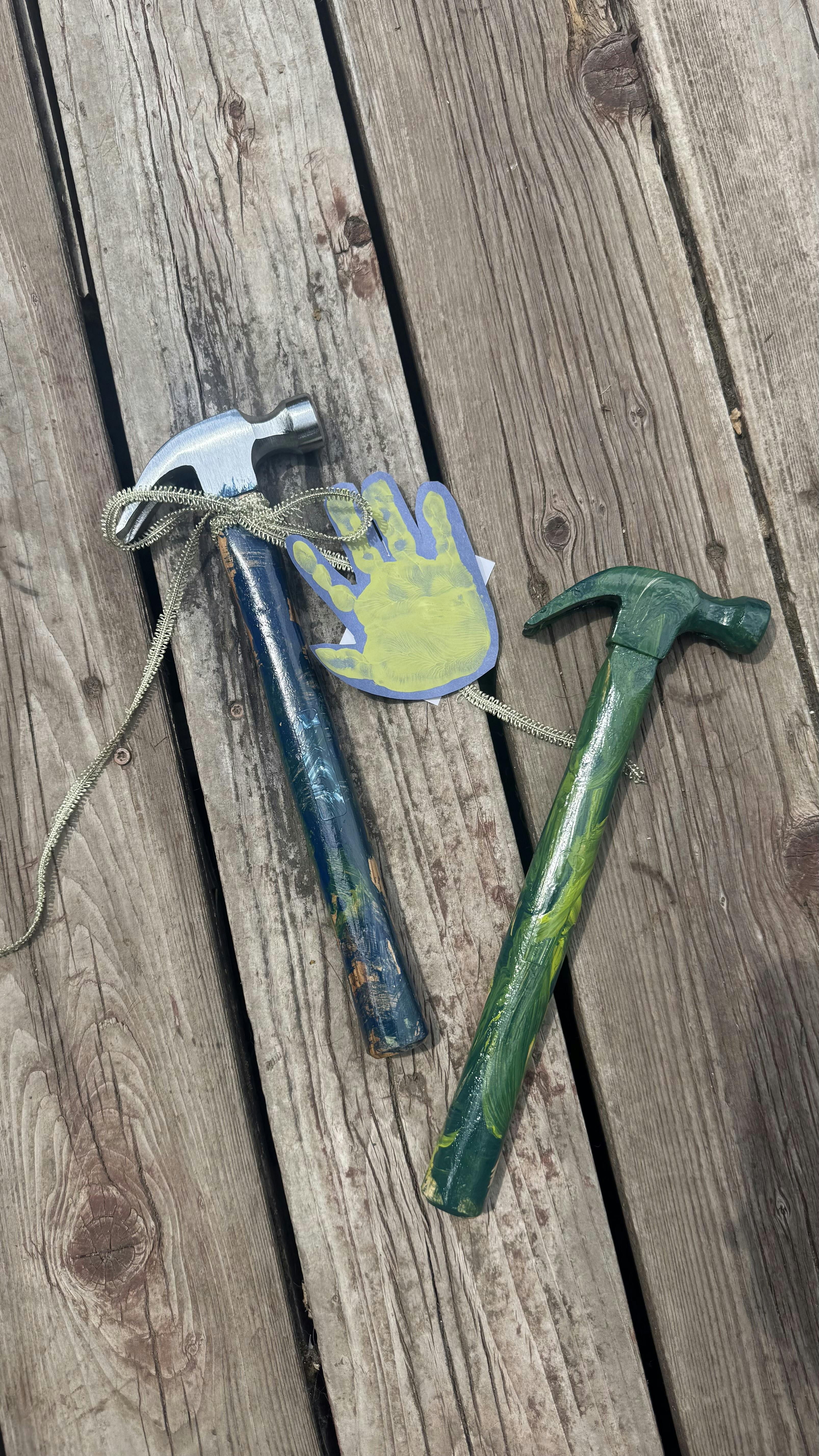 Two painted hammers tied together with a paper handprint cutout