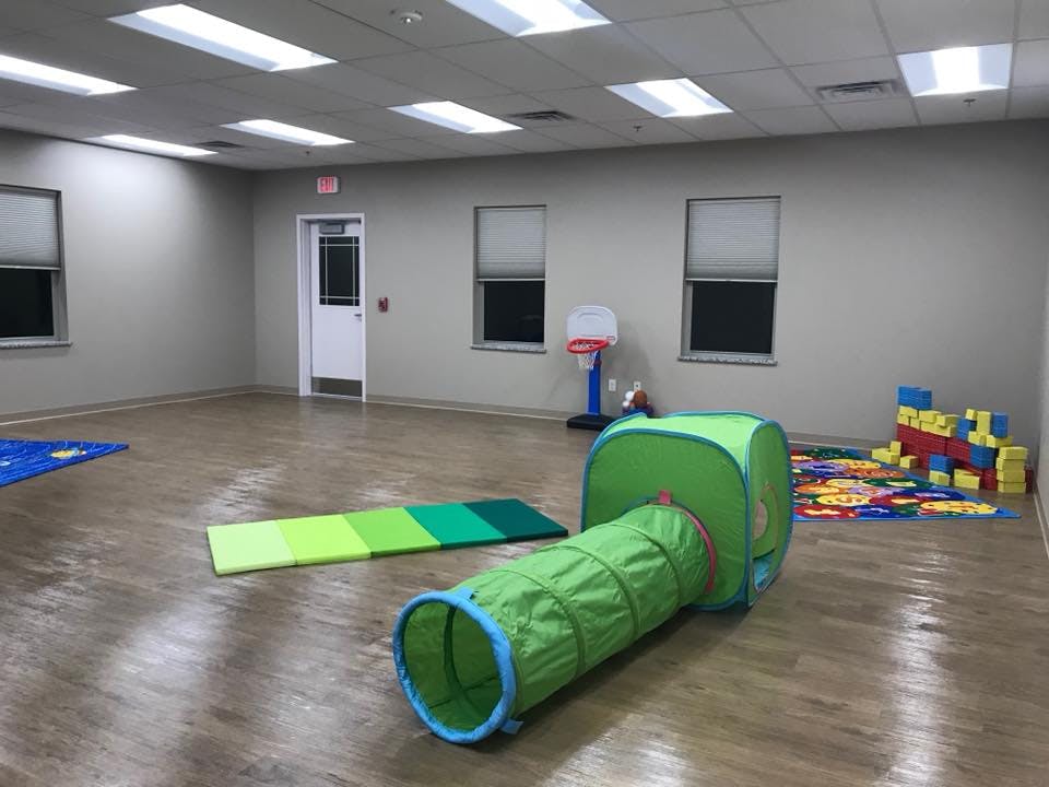 Empty room with a green play tunnel, mats, and building blocks