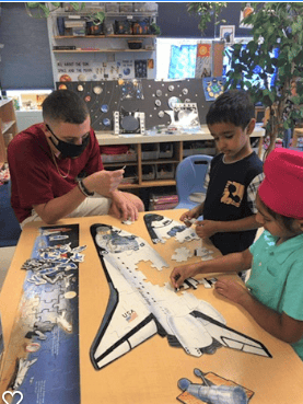 Adult and two children assembling a space shuttle puzzle