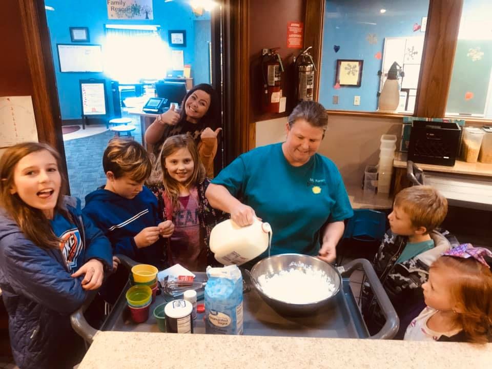 Person pouring liquid into a bowl with several children watching