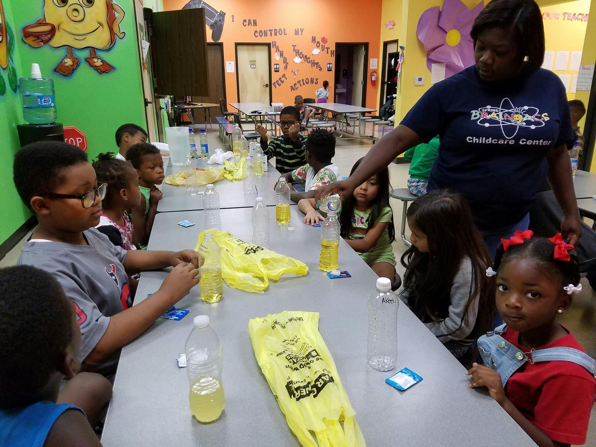Adult supervising children at a table with bottles and yellow bags