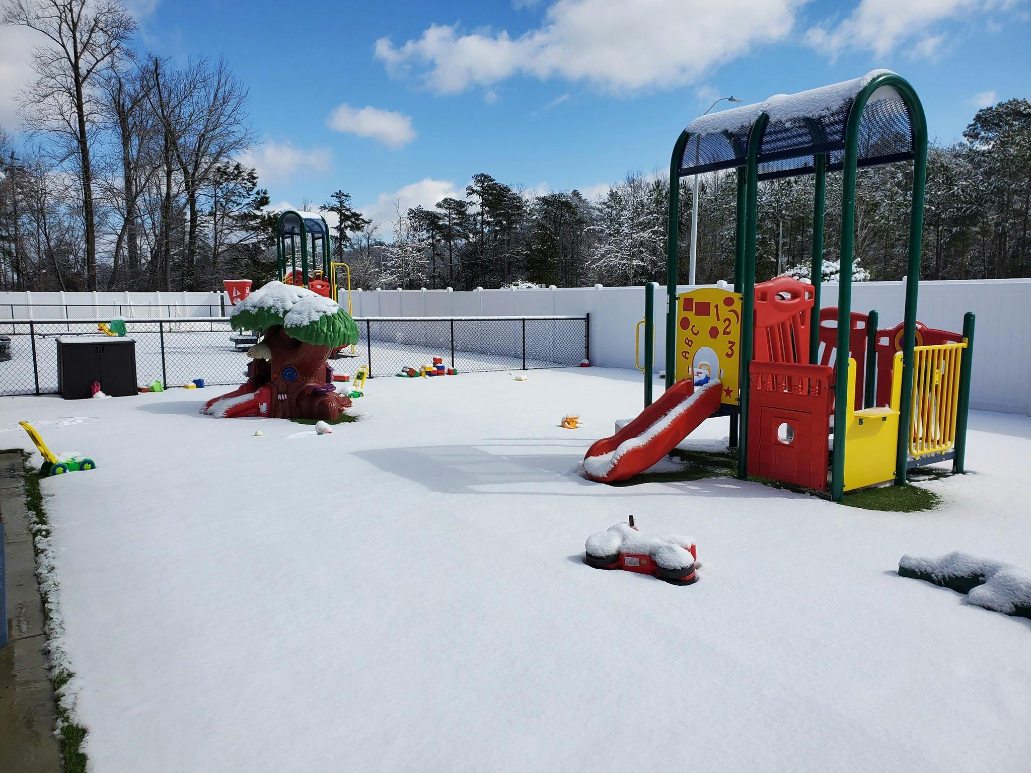 Playground covered in snow with a slide and climbing structure