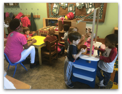 Adult and children in a classroom playing with toys